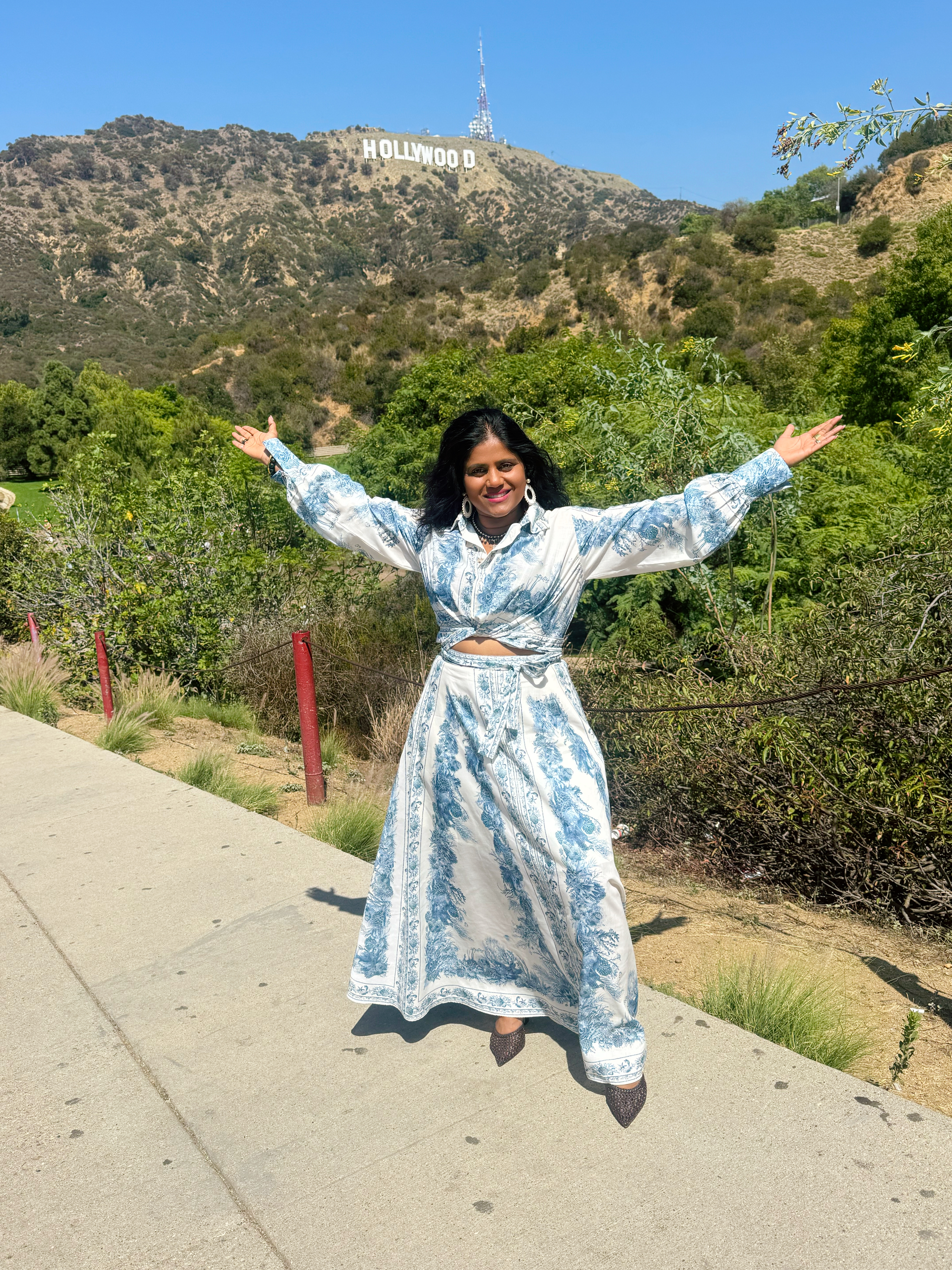 Kohila Sivas standing with open arms beneath the Hollywood sign
